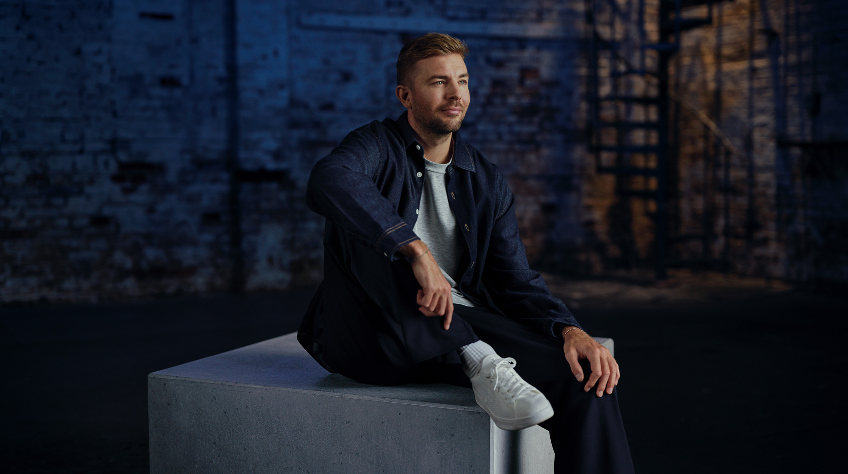 Horizontales Motiv von Fußballweltmeister und Buchautor Christoph Kramer im Interview-Raum mit Industriecharakter.