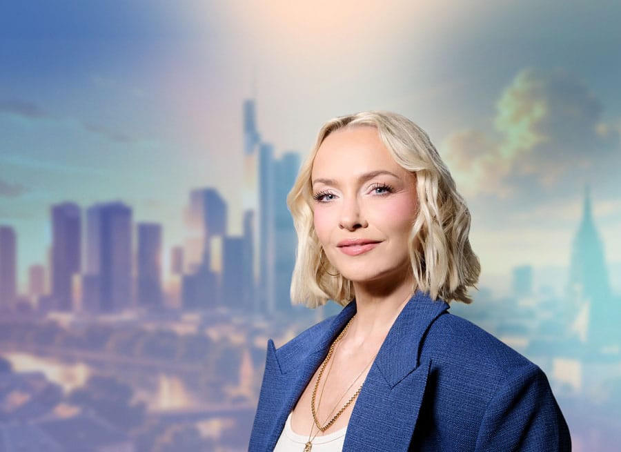 Podcast-Hostin Janin Ullmann lächelt in die Kamera. Im Hintergrund die Skyline von Frankfurt.